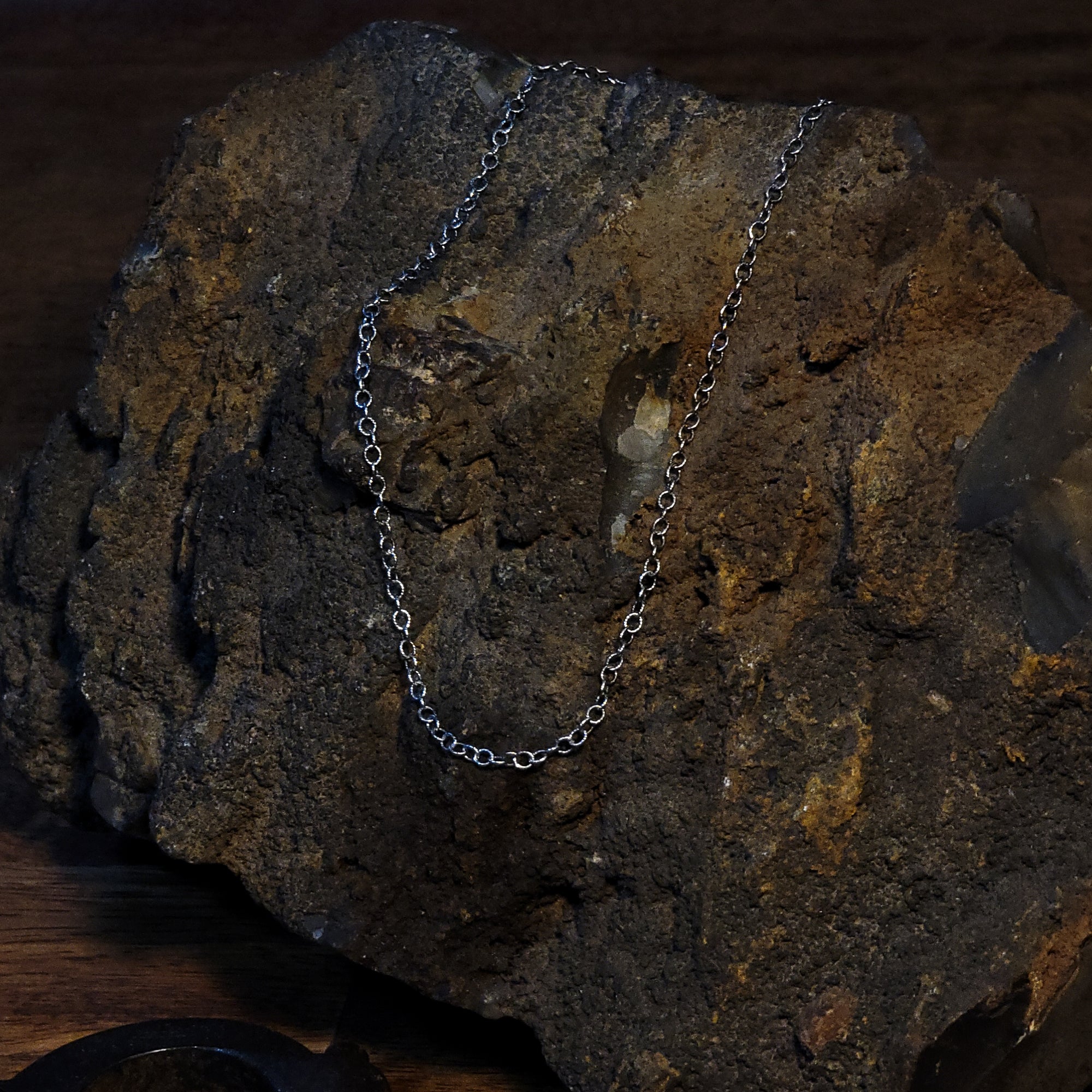 This is a photo of the chain on a rough rock. It is draped over the rock to show different angles of the chain. 