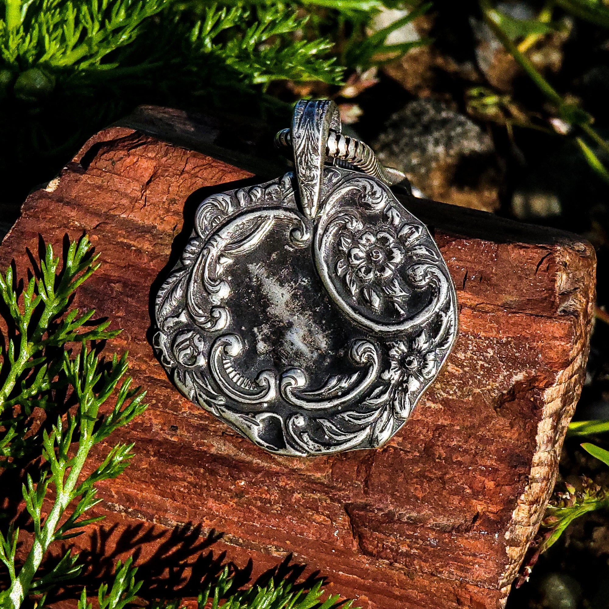 Our Art Nouveau Garden of Silver pendant evokes the wild beauty of a garden. The intricate wreath design features organic shapes and textures of flowers and vines made from sterling silver, with a unique tarnished finish that brings out the detailing